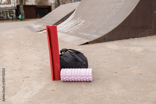 A black bag and fitness gear sit by the ramps at the skate park in the afternoon light