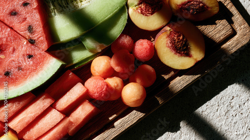 Fresh sliced watermelon, cantaloupe and peach on a wooden board. Healthy organic summer fruits for snack or salad. Culinary arrangement for nutrition, diet and gourmet food presentation.