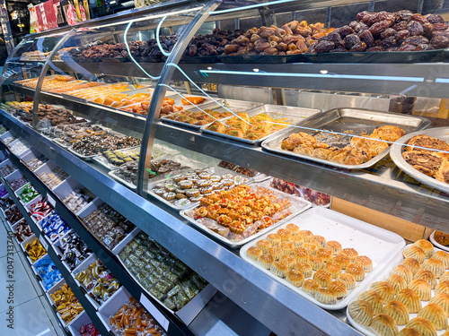 Display of freshly prepared Middle Eastern pastries and sweets in a bakery section of Dubai market.