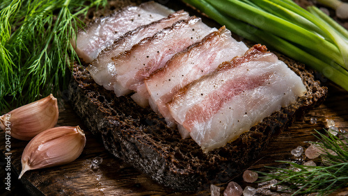 macro of thin slices of Ukrainian salo cured pork fat arranged on a thick slice of dark rye bread