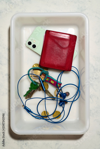 Personal belongings placed in the plastic tray at a security checkpoint.