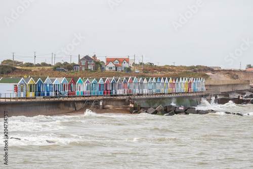 Promenade lined with a row of colourful beach huts on a overcast day in Southwold, Suffolk, UK