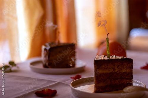 Foto Chocolate cake slice with extinguished candle on white plate