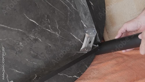 mens hands fasten the table leg, close-up, slow motion
