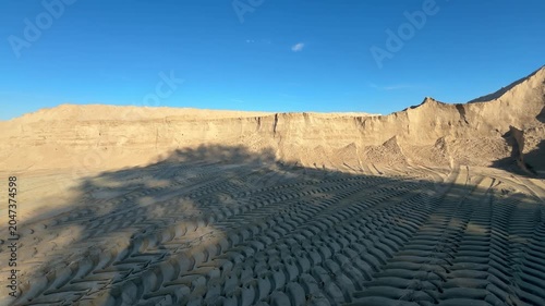 Large sand quarry with tire tracks under blue sky