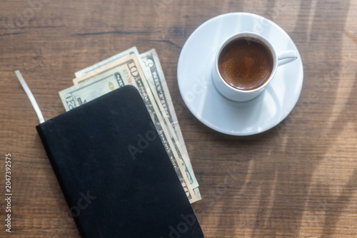 Obraz na plátně Close-up of a cup of black coffee and cash money placed inside an open ledger no