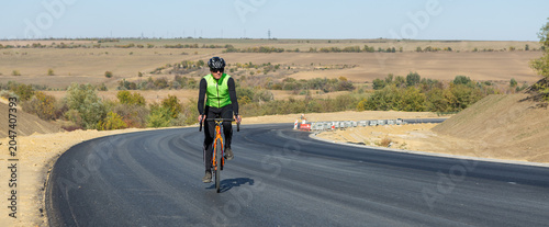 Cyclist riding bicycle on road against clear sky