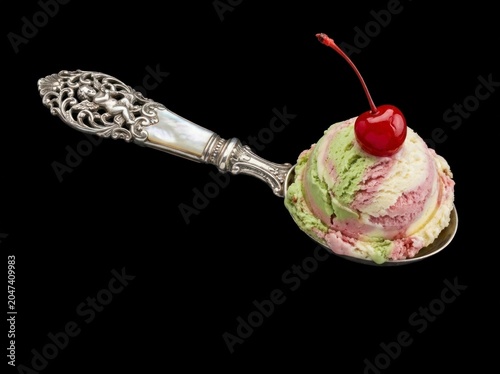 Colorful ice cream with cherry on spoon.