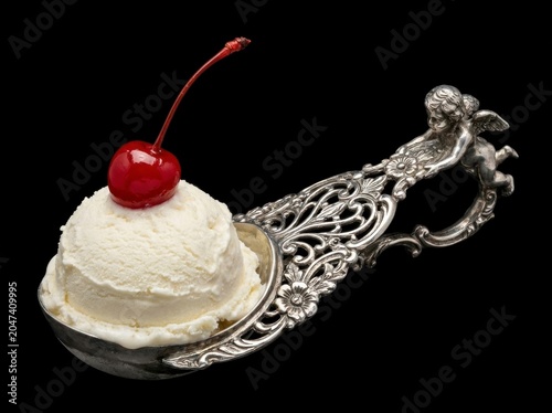 Delicious ice cream with cherry on ornate spoon.