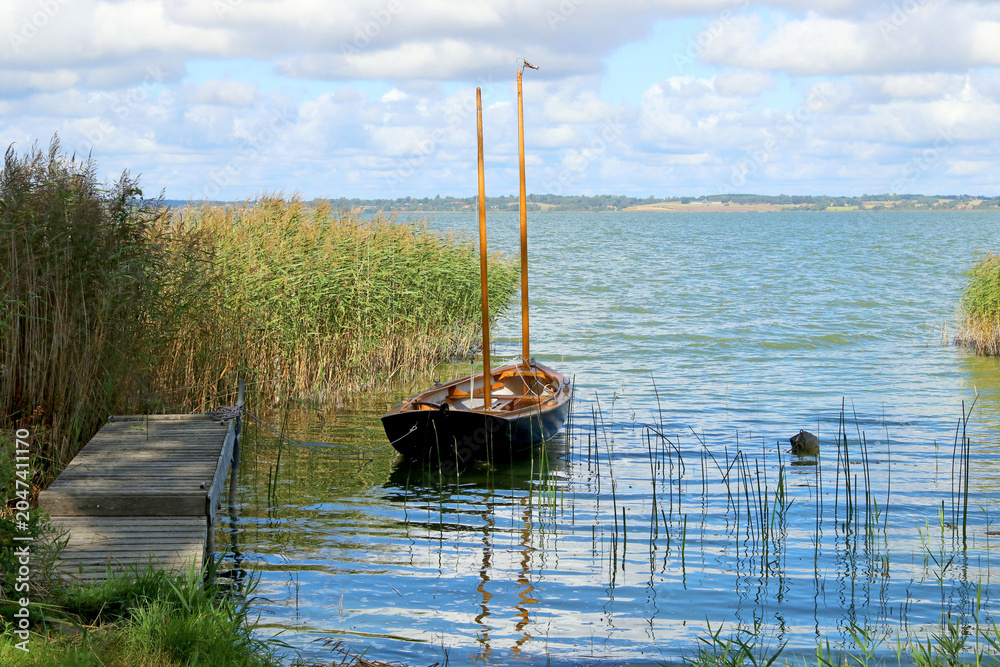 Naklejka premium A wooden boat is moored at a small wooden pier.