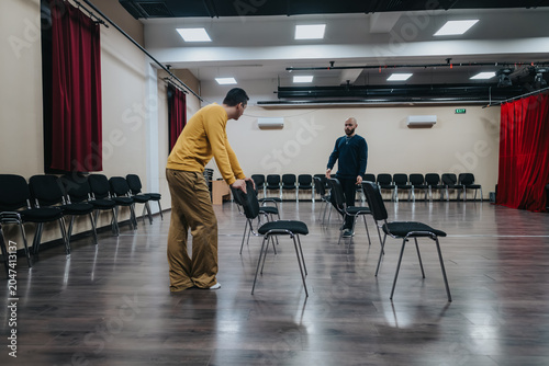Fotografija Young actors arrange chairs in an empty rehearsal room during a theater practice