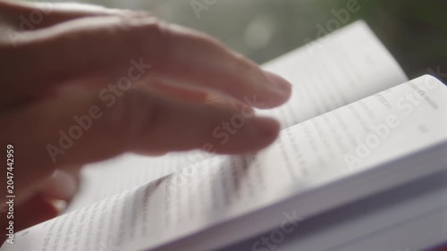 Close-up, woman turning a page of a book with her hand while reading