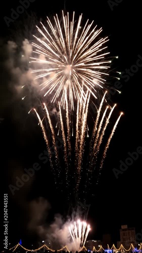 Golden sparkling firework burst over a dark city skyline.