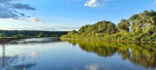 Summer landscape on the Dnieper River, green trees and reflections in the water.