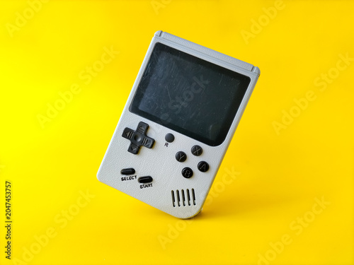 Foto Retro handheld gaming console on a bright yellow background.