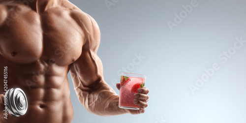 Muscular man holding dumbbell and glass of refreshing drink, showcasing strength and fitness