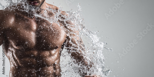 Muscular man splashing water, showcasing strength and vitality in dynamic pose. image captures energy and movement