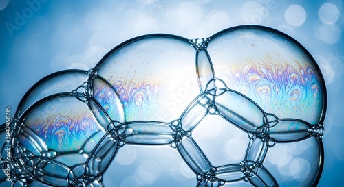 Interconnected soap bubbles, iridescent light reflections on a blue background. Delicate, transparent bubble cluster, a beautiful abstract liquid structure for science, cleaning