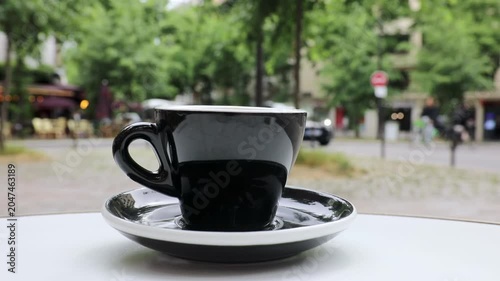 Cup of fresh hot coffee on the table of an outdoor cafe in Paris, France.