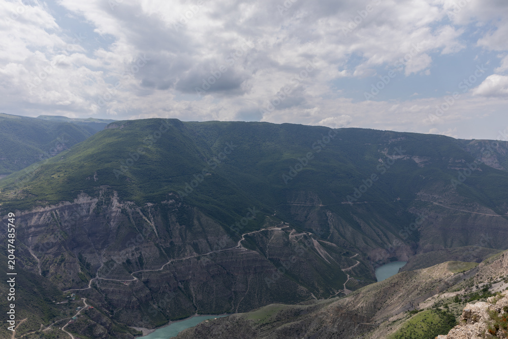 Fototapeta premium Wide scenic landscape of the Small Sulak Canyon with winding turquoise river, steep rocky slopes and cloudy sky, Dagestan Republic, Russia, Caucasus region