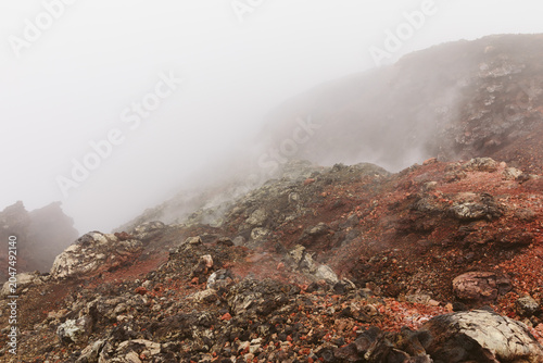 Foto Mist and steam drift over rugged red volcanic rocks in the Northern Breakthrough