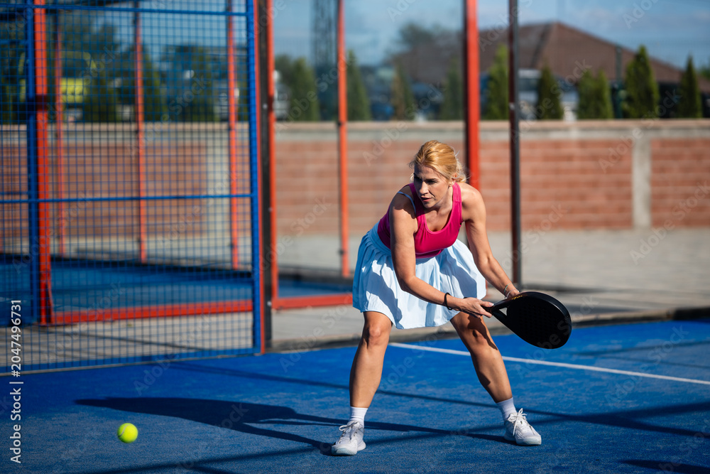 Obraz premium Woman playing padel on a blue court with racket