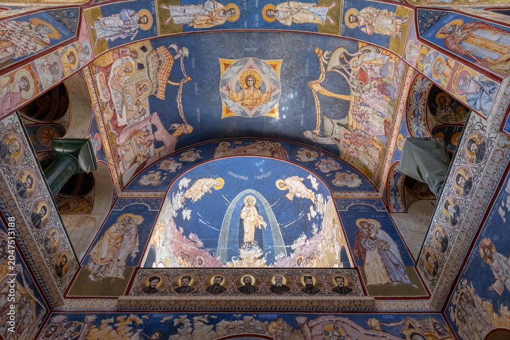 Obraz premium Bar, Montenegro - August 10, 2025: Wide view of Orthodox Christian frescoes and iconography covering the arched ceiling inside the Church of St. Jovan Vladimir in Bar, religious art and architecture