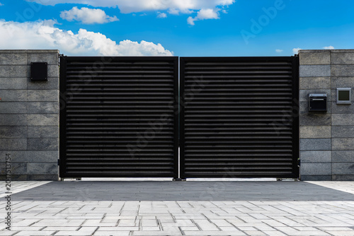 Modern property entrance with closed swing gate, mailbox