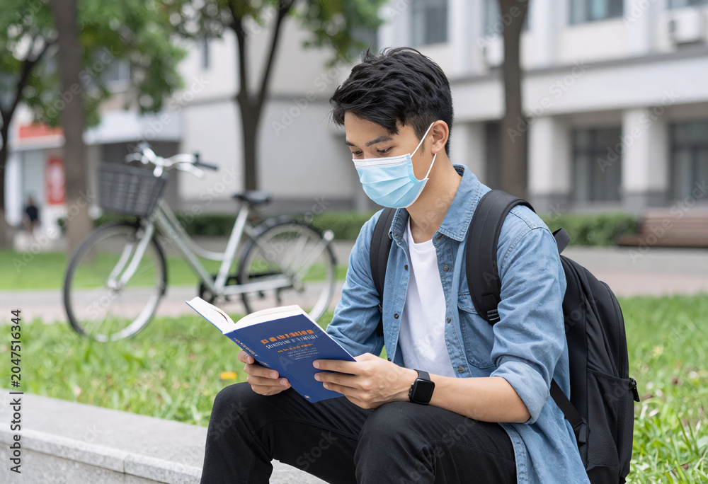 Obraz premium Young adult university student reading political philosophy in urban park