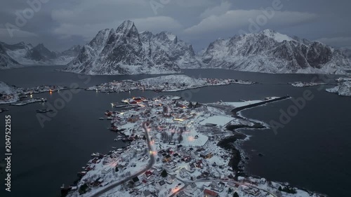 Aerial view of snow-covered fishing village on narrow peninsula at twilight