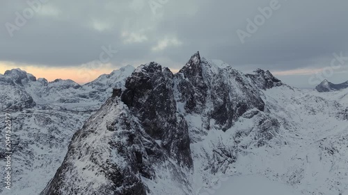 Aerial dusk view of jagged snow-covered mountain ridge and steep rocky summit