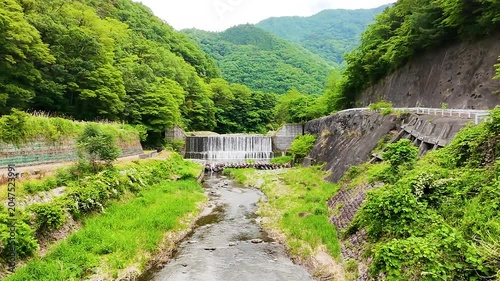 山から続く透明な川の流れと森林に包まれた爽やかなドローンイメージ