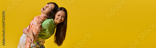 Fotografía Couple sharing joyful moments in colorful outfits against a vibrant yellow backg