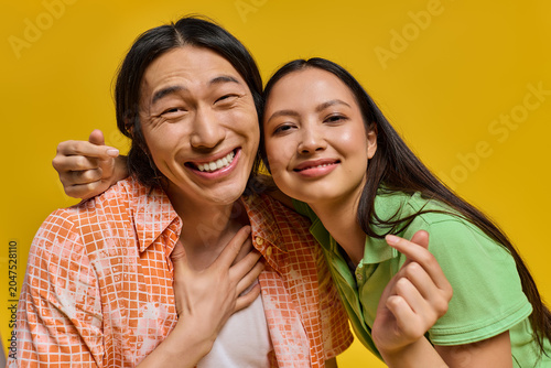 Fotografia Joyful moments shared between a stylish couple against a vibrant yellow backdrop