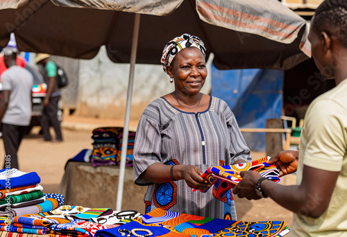 African Woman Selling Colorful Fabrics at Outdoor Market
