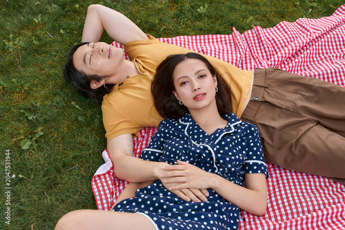 Joyful moments of a stylish couple enjoying a sunny picnic in a lush green park