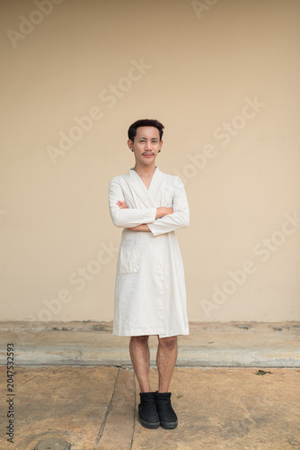 Full Body Portrait of Thai Non-Binary Gay Man Arms Crossed Against Plain Wall