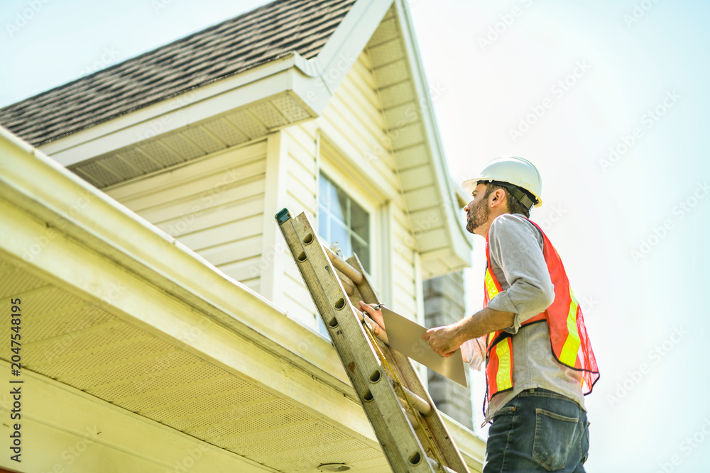 Fototapeta premium Man with a white hard hat holding a clipboard, inspect house