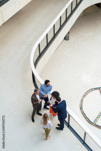Business colleagues discussing over tablet PC in office corridor