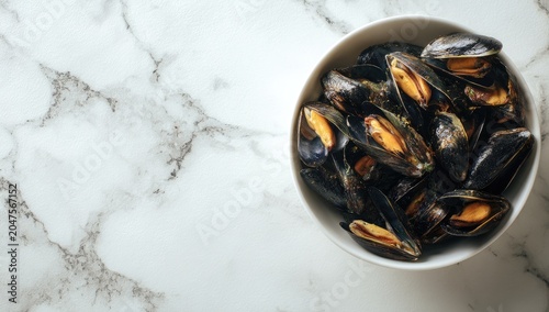 A bowl of fresh mussels on a textured white marble surface