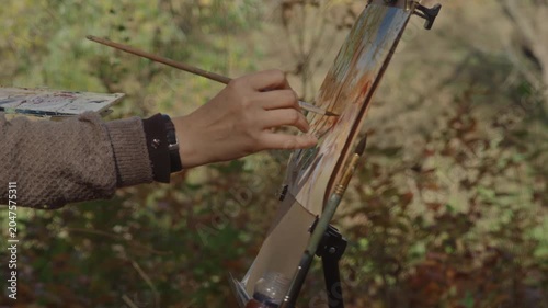 Close-up, the artist paints a watercolor landscape in an autumn forest