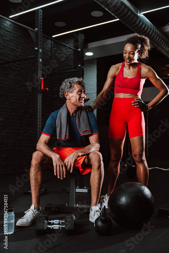 Fit senior man in the gym with his personal trainer.