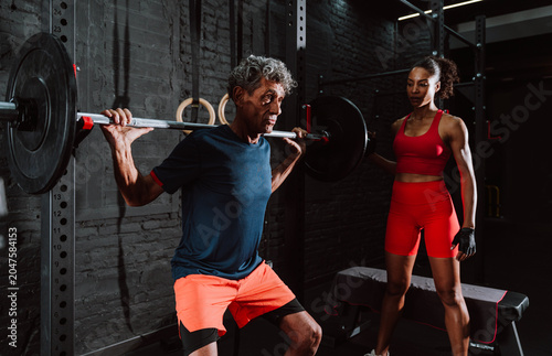 Fit senior man in the gym with his personal trainer.