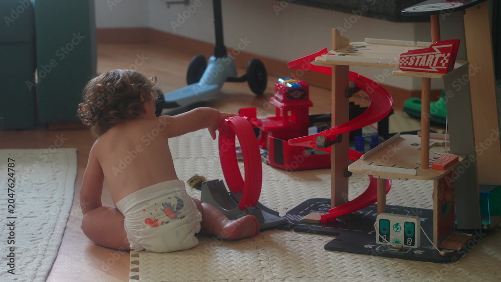 Αυτοκόλλητο Toddler playing with toy car track on floor during morning playtime at home in l