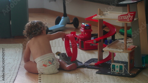 Φωτογραφία Toddler playing with toy car track on floor during morning playtime at home in l