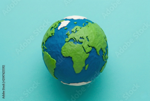 Handmade plasticine model of planet earth isolated on a clean blue background.