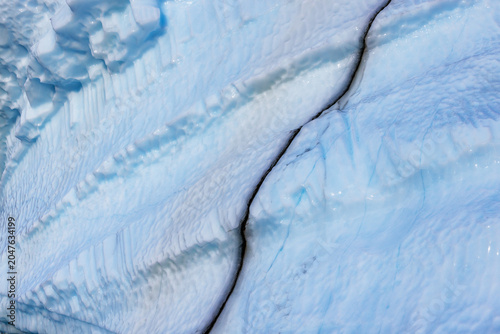 Iceberg showing the weathered and textured surface with a black volcanic ash seam, formed when the ash is trapped between layers of snow and them compressed over centuries.