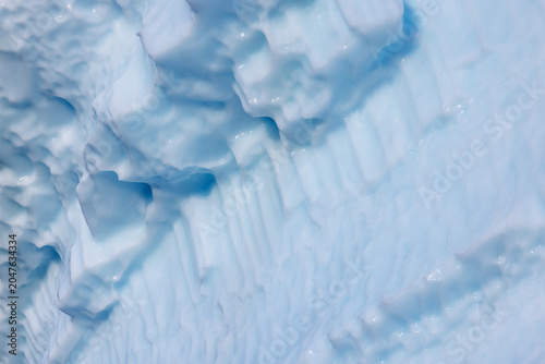 Closeup of of a blue iceberg in Northeast Greenland National Park, showing the the weathered and textured surface. Abstract background with space for text.
