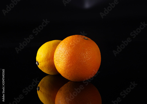 Two oranges on a black background with side lighting.