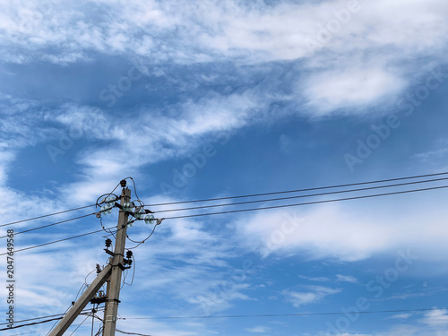Utility Pole And Power Lines Against Cloudy Blue Sky
